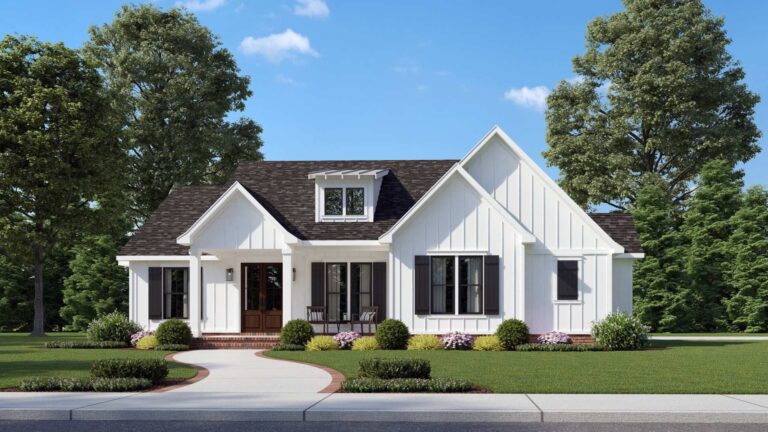 A front view of a modern farmhouse-style home with a charming and welcoming design. The exterior features white board and batten siding, a dark shingled roof, and black shutters framing the windows. The entryway includes a covered front porch supported by white columns, leading to a set of double wooden front doors. A small dormer window above the porch adds architectural interest to the roofline. The front yard is beautifully landscaped with a curved walkway, neatly trimmed bushes, and colorful flower beds. Tall trees provide a serene backdrop under a clear, blue sky.